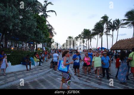 Menge von Menschen zu Fuß auf Deerfield Beach, Florida, nach Einbruch der Dunkelheit in Erwartung des Feuerwerks mit Palmen, Tiki Hut und Pier hinter am 4. Juli 2017 Stockfoto