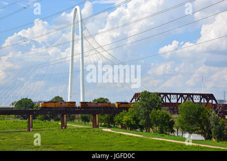 Eine Union Pacific Güterzug verlassen downtown Dallas, über Trinity River und durch die Kabelbrücke Margaret Hunt Hill Stockfoto