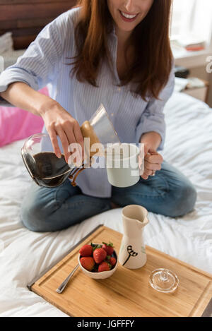 Kaukasische Frau im Bett Kaffee gießen Stockfoto