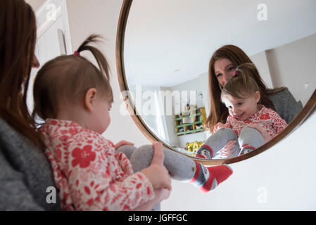 Reflexion der kaukasischen Mutter und Baby Tochter im Spiegel Stockfoto