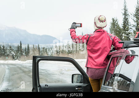 Kaukasische Frau im Auto im Winter Panorama fotografieren Stockfoto