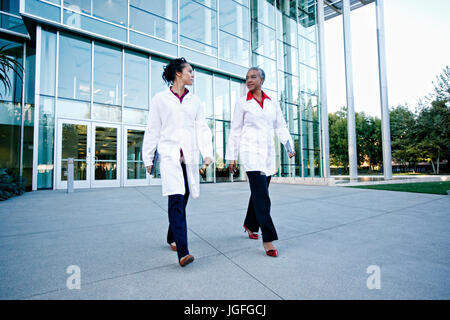 Ärzte gehen und sprechen im Freien im Krankenhaus Stockfoto