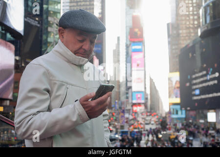 Hispanic Mann SMS auf Handy in überfüllten Stadt Stockfoto