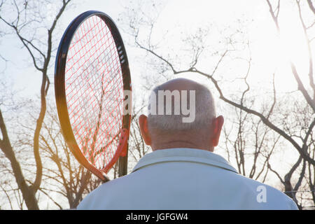 Rückansicht des Hispanic Mann hält Tennisschläger Stockfoto