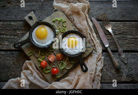 Spiegeleier in Gusseisen Pfannen auf Schneidebrett Stockfoto