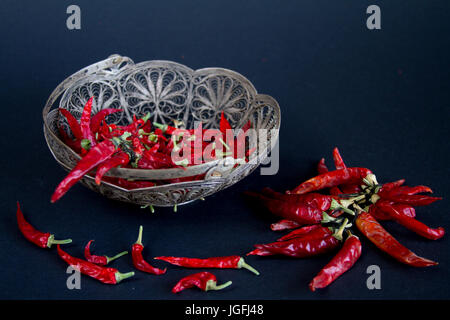 Rote Chilischote in eine silberne Vase auf einem schwarzen Hintergrund. Stockfoto