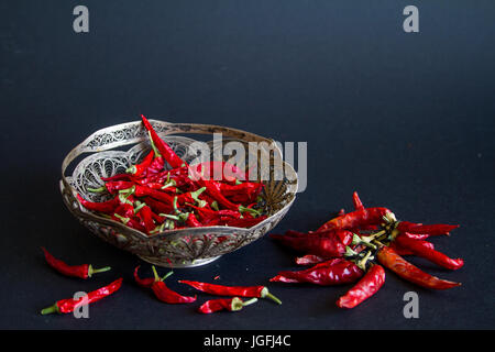 Rote Chilischote in eine silberne Vase auf einem schwarzen Hintergrund. Stockfoto