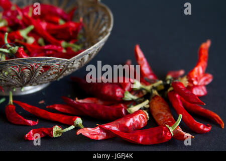 Rote Chilischote in eine silberne Vase auf einem schwarzen Hintergrund. Stockfoto