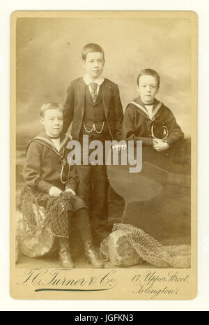 Originales Sepia-farbiges Cabinet Card Studio-Porträt mit Hintergrund am Meer von 3 jungen viktorianischen Jungen, die in Matrosenanzügen posierten, datiert 1888, Islington, London, Großbritannien Stockfoto