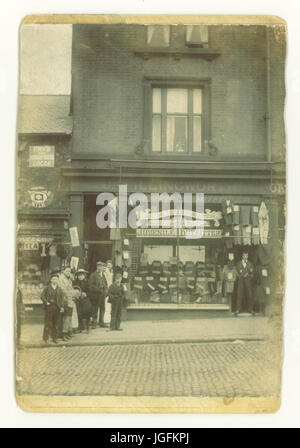 Edwardian Foto von J.A.S (James) Illingworth Juvenile Outfitters, Schneider und Textilhändler. 18 Attercliffe Road, Sheffield, South Yorkshire, England, Großbritannien Assistenten/Personal und Kunden aus dem Supermarkt nebenan haben auch für das Foto, während der Eigentümer der Schneider ein würdiges und humorlosen Pose unterhält. Circa 1905. Stockfoto