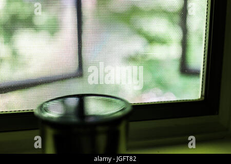 Reflexion des Netzes Fenster- und grünen Laub in Wasser oder Tee auf Fensterbank Stockfoto