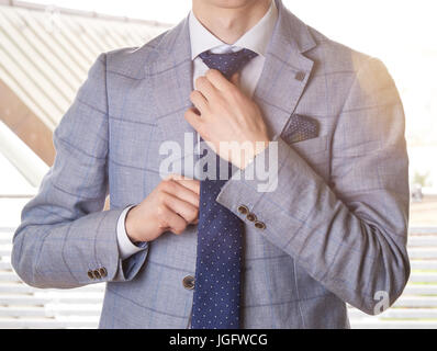 Unkenntlich Geschäftsmann ankleiden für die Arbeit, seine Krawatte anpassen. Sanften Farben mit einem Blendenfleck. Stockfoto