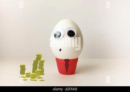 Business-Konzept. Profitables Geschäft. Ein Ei, die Zunge zu zeigen. Ei mit lustigem bemalte Gesicht auf einem weißen Hintergrund. Foto für Ihr Design. Mit einem l Stockfoto