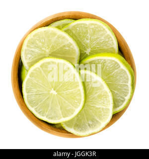 Limettenscheiben in Holzschale. Frisch geschnittene unreife grüne essbaren Zitrusfrüchte Scheiben. Key Lime, Citrus Aurantiifolia. Isolierte Makrofoto Essen hautnah. Stockfoto