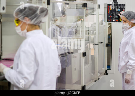Ein Mitarbeiter betreut die Verpackung der medizinische Pillen. Zwei weibliche Arbeiter Produktionskontrolle in Pharmafabrik. Stockfoto