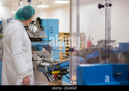 Pharmazeutischen Arbeitnehmerin steuern die medizinische Pille Verpackungslinie. Stockfoto