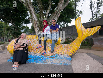 Indonesische Touristen posieren auf einem riesigen Fisch Skulptur im Tempel Pura Ulun Danu Bratan See, Insel Bali, Bedugul, Indonesien Stockfoto