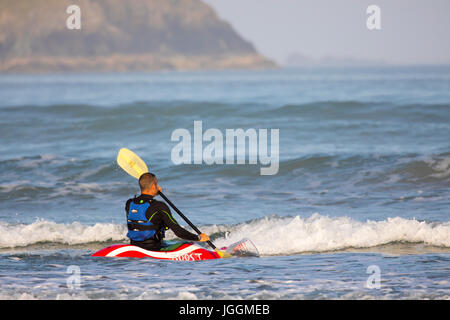 Ein Meer Kanuten oder Kajakfahrer paddeln durch die Wellen an den beliebten Surf Strand Polzeath auf der Suche nach einer Welle zu fahren mit dem Kanu, Cornwall, UK Stockfoto