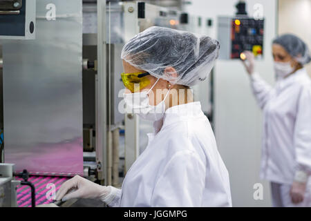 Pharmazeutischer Arbeiter Controlling die Verpackung der medizinische Pillen. Pharmazeutische Technolgists tragen von Schutzkleidung. Stockfoto