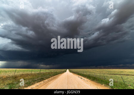 Unbefestigte Straße und dunkle Wolken mit stürmischem Himmel über einem Feld in Colorado Stockfoto