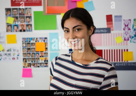 Portrait der schönen Frau, die gegen Haftnotizen in Kreativbüro Stockfoto