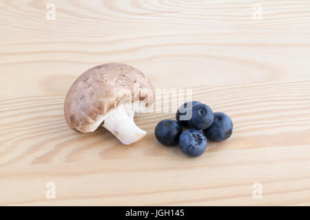 Kastanien Pilz und vier Heidelbeeren auf Holzbrett Stockfoto