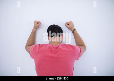 Deprimiert männliche Führungskraft mit erhobenen Armen stützte sich auf der Wand im Büro Stockfoto