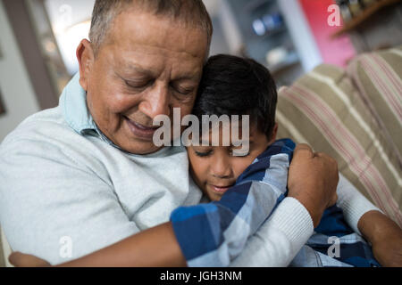 Junge umarmen Großvater beim Sitzen auf dem Sofa zu Hause Stockfoto