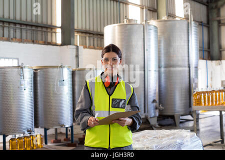 Porträt von weiblichen Techniker schreiben in Zwischenablage am Öl-Fabrik Stockfoto