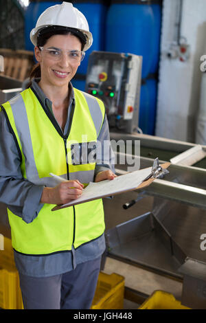 Porträt von weiblichen Techniker schreiben in Zwischenablage am Öl-Fabrik Stockfoto