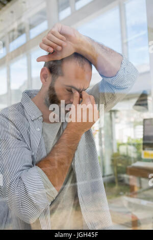 Gespannten Designer stützte sich auf Fenster gesehen durch Glas Stockfoto