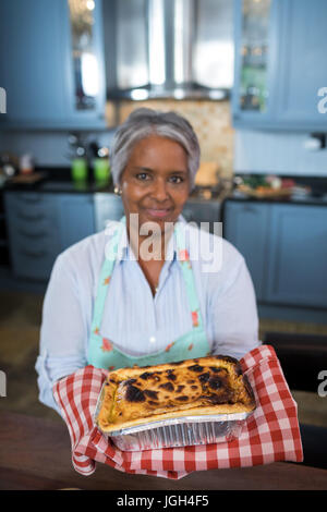 Porträt von senior Frau zeigt gebackene Speisen in der Küche zu Hause aufhalten Stockfoto