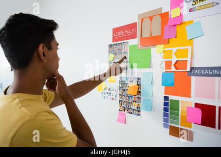 Nachdenklicher Mann zeigte auf Haftnotizen in Kreativbüro Stockfoto