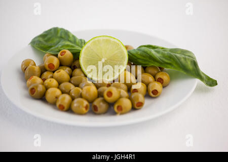 Nahaufnahme von Oliven mit Zitrone und Kräutern auf Tisch Stockfoto