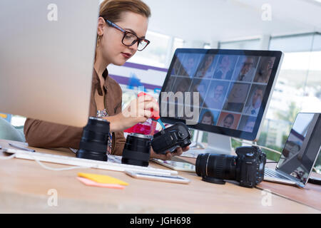 Weibliche Führungskraft Reparatur einer digitalen Kamera im Büro Stockfoto