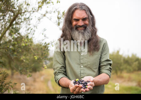 Porträt von glücklicher Mann hält geerntete Oliven in Hof Stockfoto