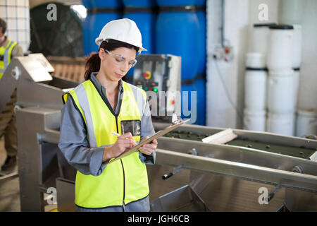 Weiblichen Techniker schreiben in Zwischenablage am Öl-Fabrik Stockfoto