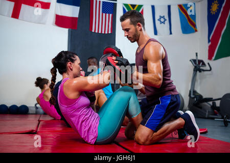 Männliche Lehrer unterstützen Boxerin im Fitness-studio Stockfoto