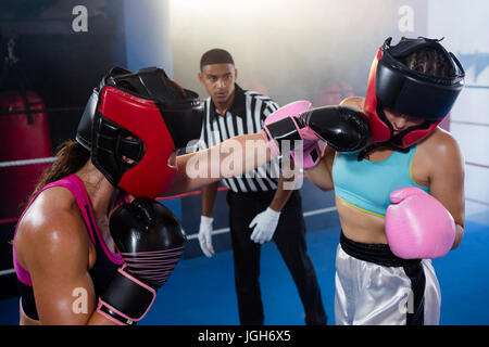 Männliche Schiedsrichter Blick auf Boxerin Stanz Konkurrent im Boxring Stockfoto