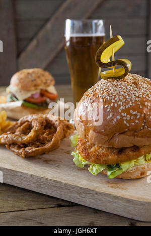 Hamburger und Zwiebel Ring mit Glas Bier auf Holztisch Stockfoto