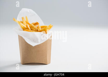 Nahaufnahme von Pommes frites in Papiertüte auf Tisch vor grauem Hintergrund Stockfoto