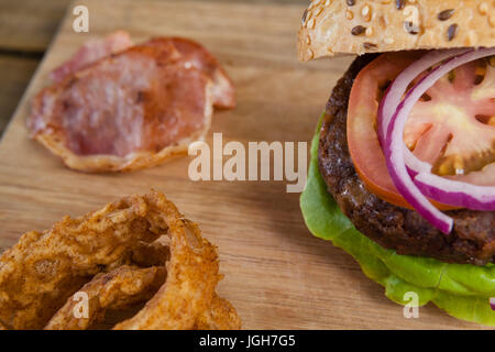 Nahaufnahme des Hamburger und Onion Rings auf Schneidebrett Stockfoto