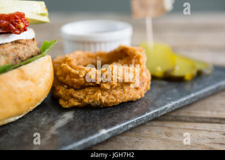 Zwiebelringe von Burger auf Schiefer am Tisch Stockfoto