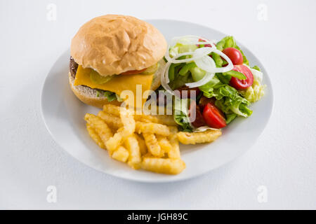 Burger mit Salat und Pommes frites in Platte auf weißem Hintergrund Stockfoto