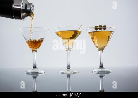 Nahaufnahme der Cocktail gegossen aus Glas mit Oliven auf den Tisch vor weißem Hintergrund Stockfoto