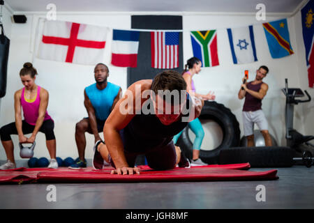 Junge männliche Athlet Taiji Push-Ups auf Trainingsmatte im Fitness-studio Stockfoto