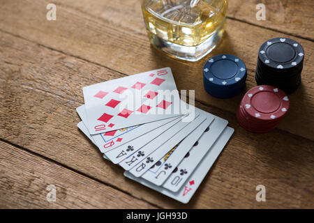 Erhöhte Ansicht der Karten und Chips von Whisky auf Holztisch Stockfoto