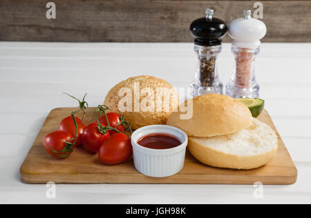 Nahaufnahme von Brötchen, Cherry Tomaten, Sauce auf Schneidebrett Stockfoto