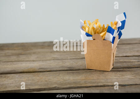 Nahaufnahme von Pommes Frites auf Holztisch gegen Wand Stockfoto