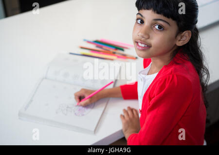 Hohen Winkel Porträt eines Mädchens, die Zeichnung in Buch am Küchentisch Stockfoto